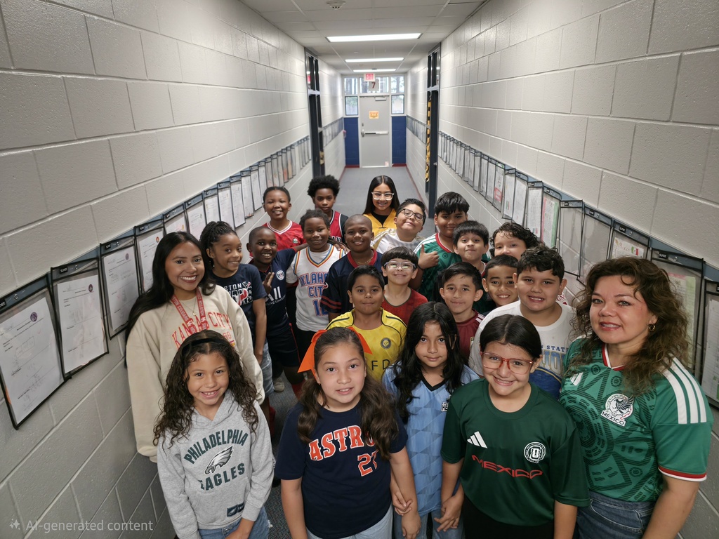 Students and two adults standing in a hallway with framed papers on the wall.