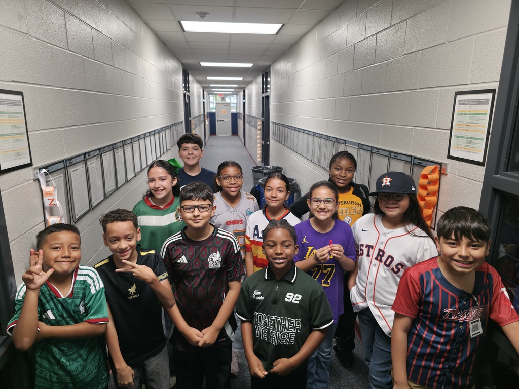 Several children posing in a corridor with painted walls and displays on either side.