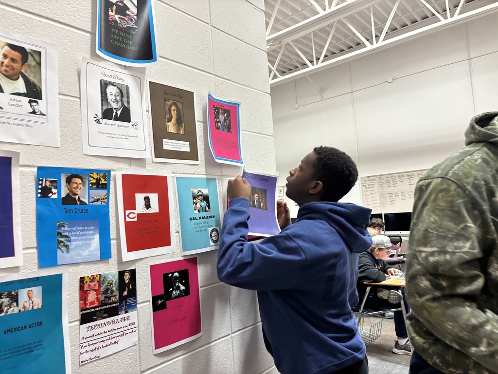Students place their poster on the wall
