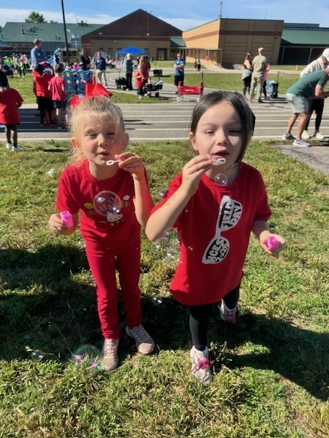 Two kindergarten students at Field Day blowing bubbles.