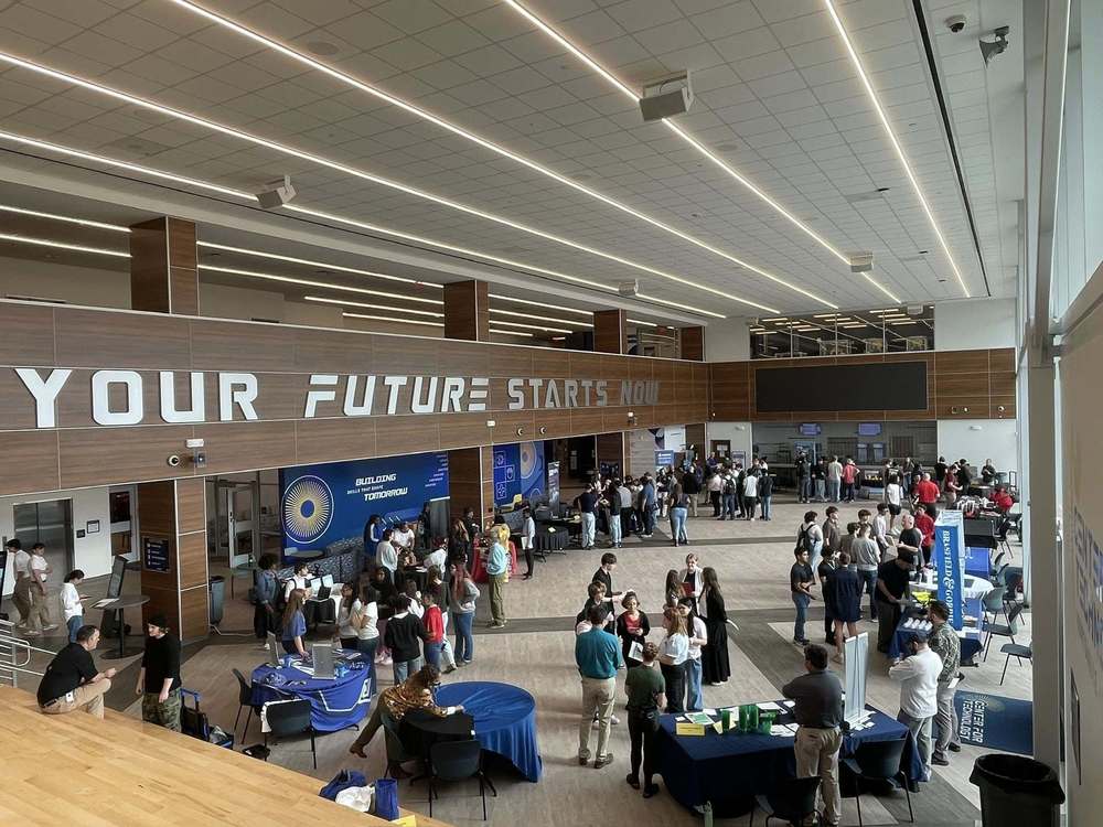 Aerial view of Huntsville Center for Technology with the words Your Future Starts Now on top of the wall. There are multiple tables and students walking around.