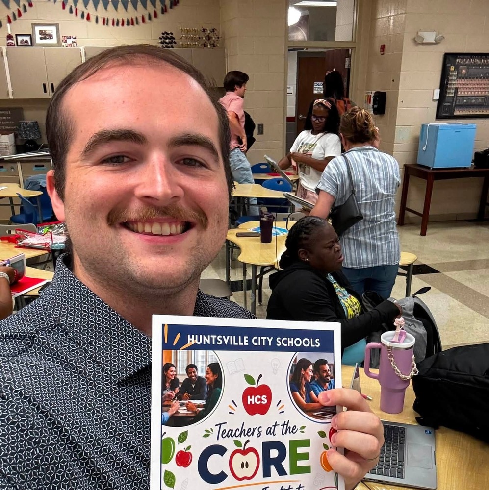 Mr. Dingo holding up a flyer that says Teachers at the Core Summer Institute