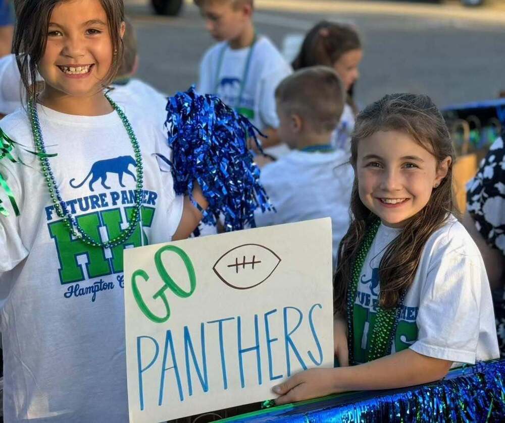 Two students holding a "Go Panthers" sign on a parade float.