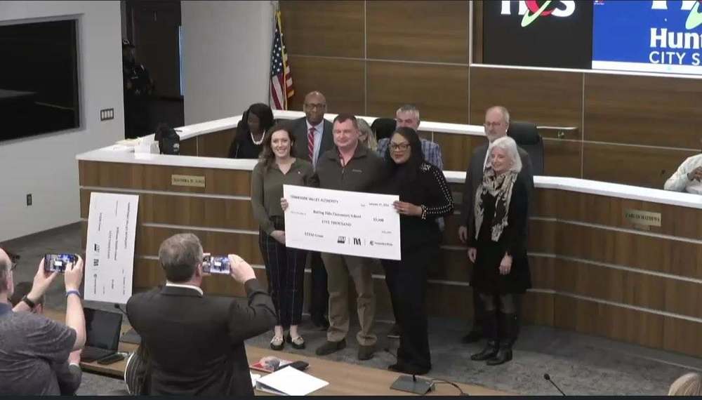 Rolling Hills Elementary staff stand with Board of Education members while holding a large TVA STEM grant check during a board meeting.