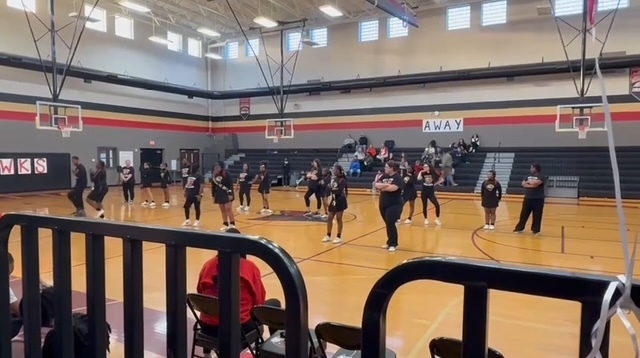 Cheerleaders dancing with teachers at the 8th grade night basketball games.
