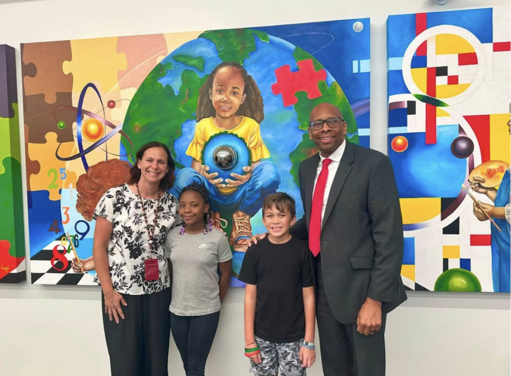 Dr. Maples the principal standing beside a girl and boy with the superintendent, Dr. Sutton
