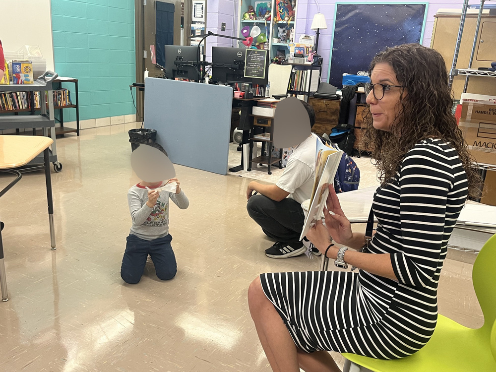 Dr. McKinney reads a book to a male student and a parent.