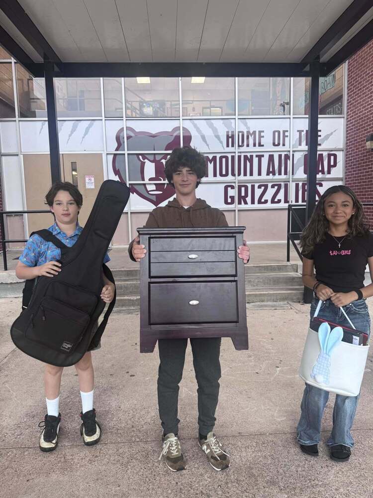 Three students with their "anything but a backpack", for underground spirit week. First student has a guitar case. Second student has a night stand and the third student has an easter basket to carry their school supplies in instead of a backpack.