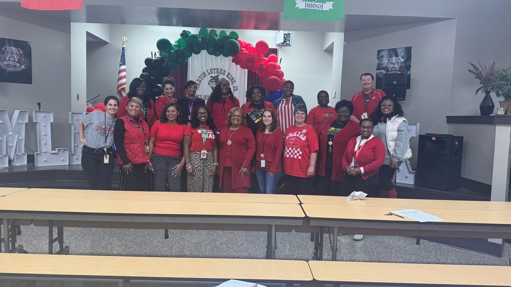 Faculty and staff posted on the stage with red attire for Red Ribbon Week 