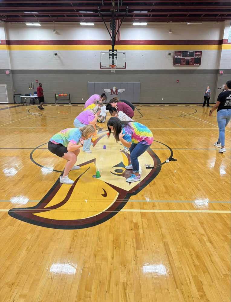 teachers standing in the middle of the gym in position to play the cup game
