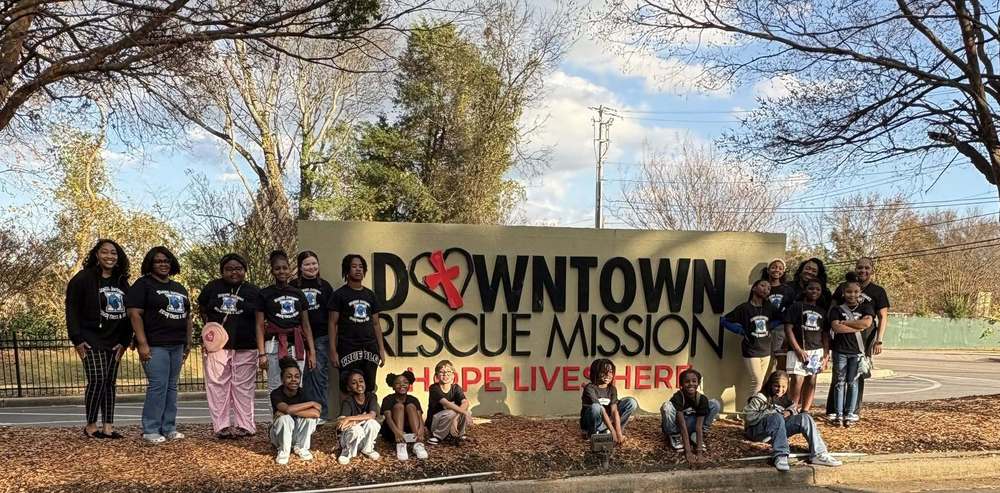 Student council members stand together smiling outside the Downtown Rescue Mission, posing for a group photo during their visit.
