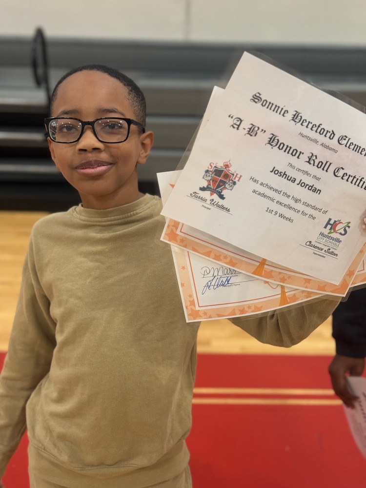 Student Joshua Jordan holding his certificates during awards ceremony