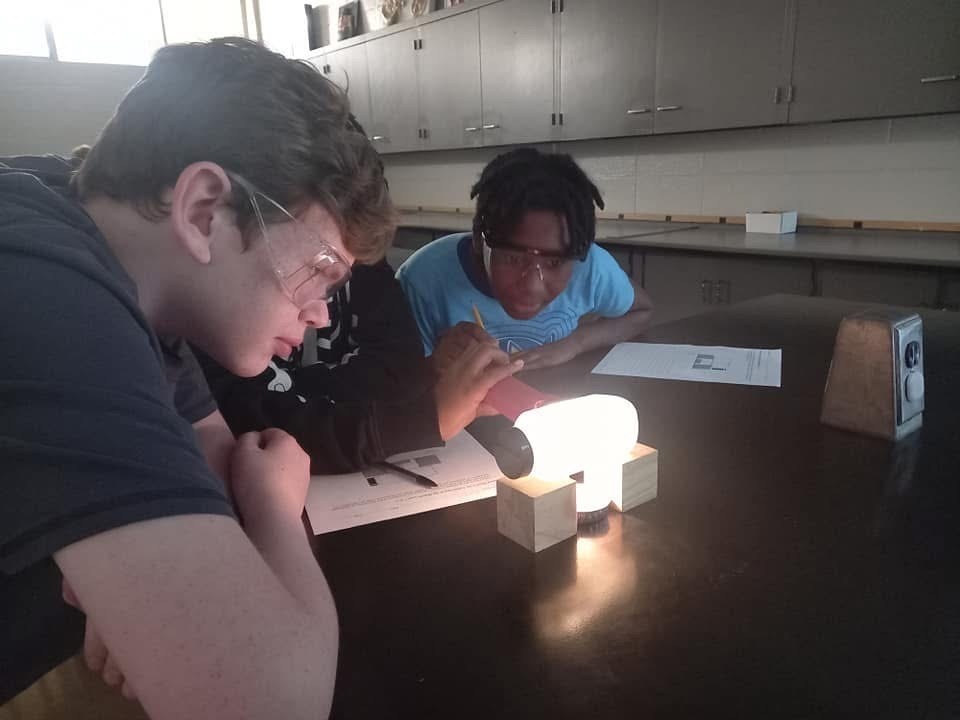 Two students looking at bottle above a candle to look at convection