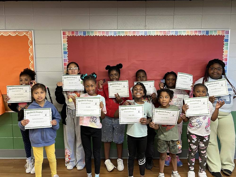 Students smile for a photo while  holding their certificates 