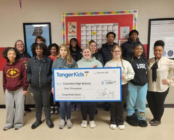 Students posing for picture holding large check from TangerKids in the amount of $1000 in the amo