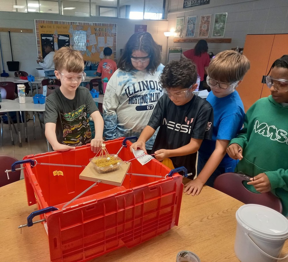 Five 6th grade students standing around a box doing an experiment about earthquakes