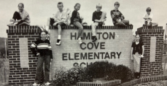 Students from the class of 2000 sitting on HCES sign