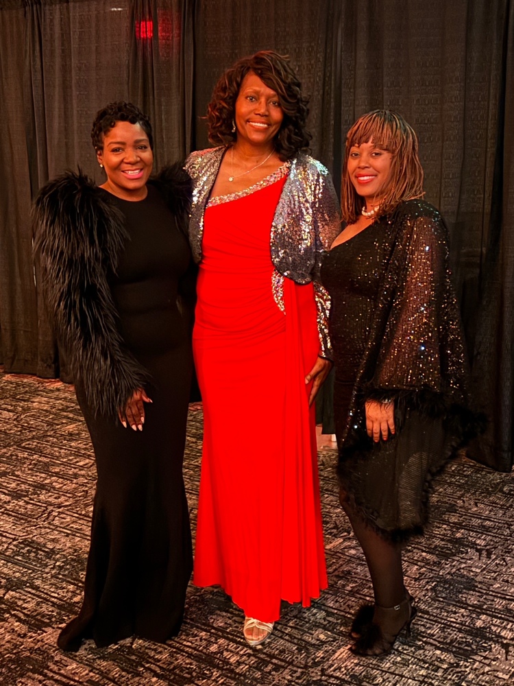 Principal Tarria Walters, Adrienne Henry, and Assistant Principal Tiffany Pogue posing  at the Golden Apple Gala  dressed in elegant formal attire standing together smiling at an indoor event.
