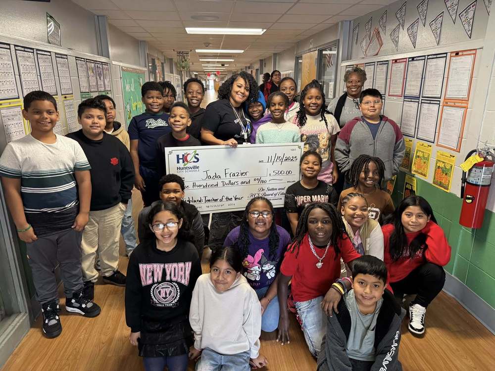Ms. Frazier stands with students, all smiling together for a group photo.