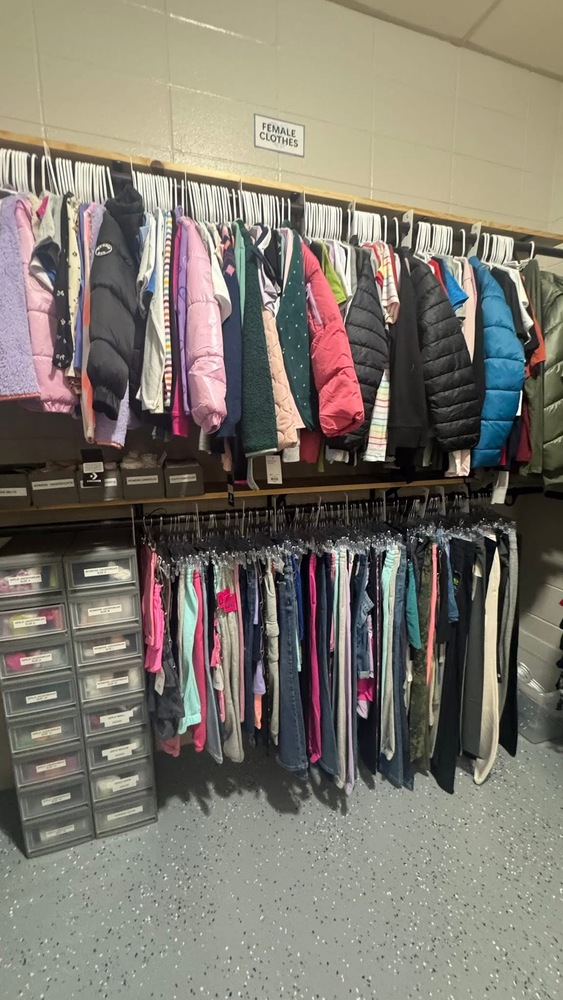 Closet at school filled with jackets, pants, and drawer with different items inside such as socks