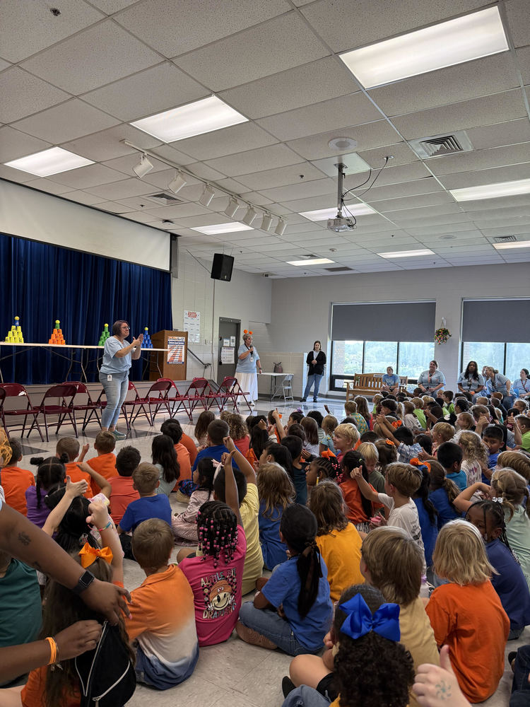 Students in the lunchroom listening to Mrs. Clark speak. Mrs. Egnew is interpreting for hearing impaired students