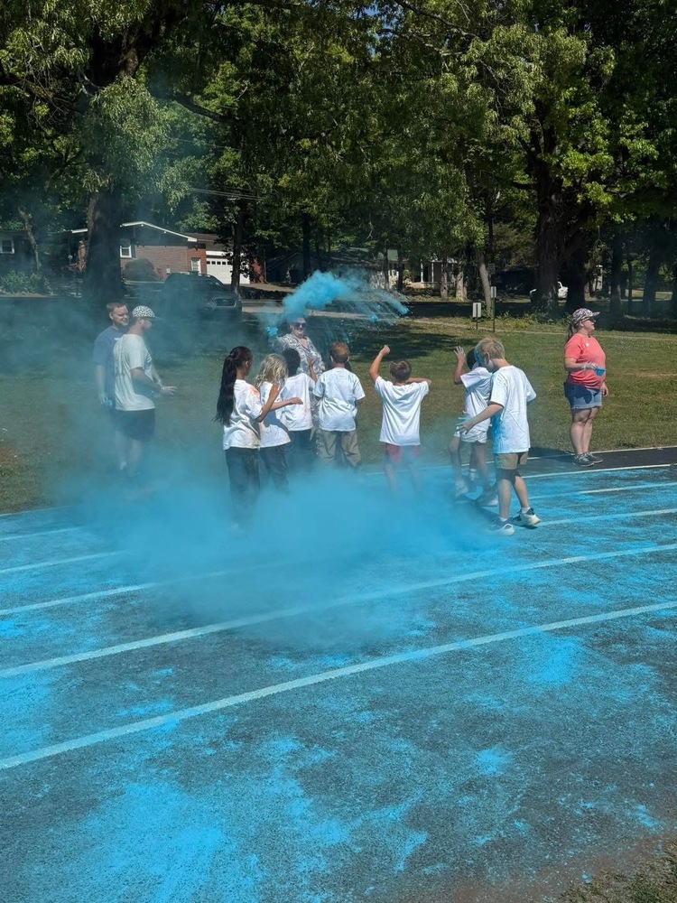 WHES students and parents  participating in a color run on the track, surrounded by blue powder.