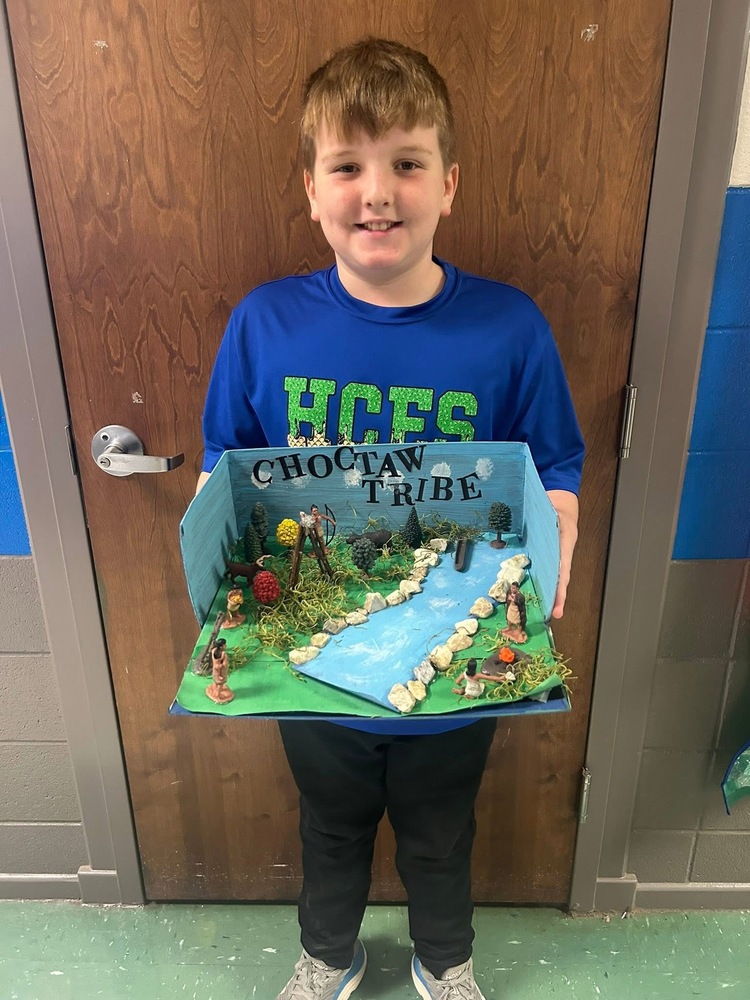 4th grader holding a model depicting life in the Choctaw Tribe