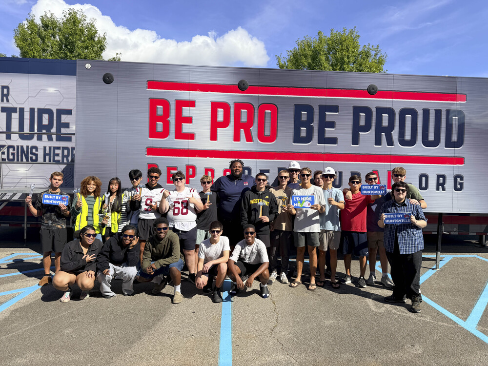 A group of students smiling and posing in front of the Be Pro Be Proud CTE simulation truck.