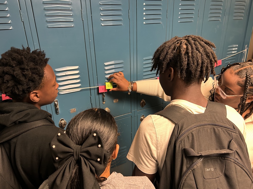 Ms. January is working with students in the hallway as they work to complete the number line taped to the wall of lockers. 