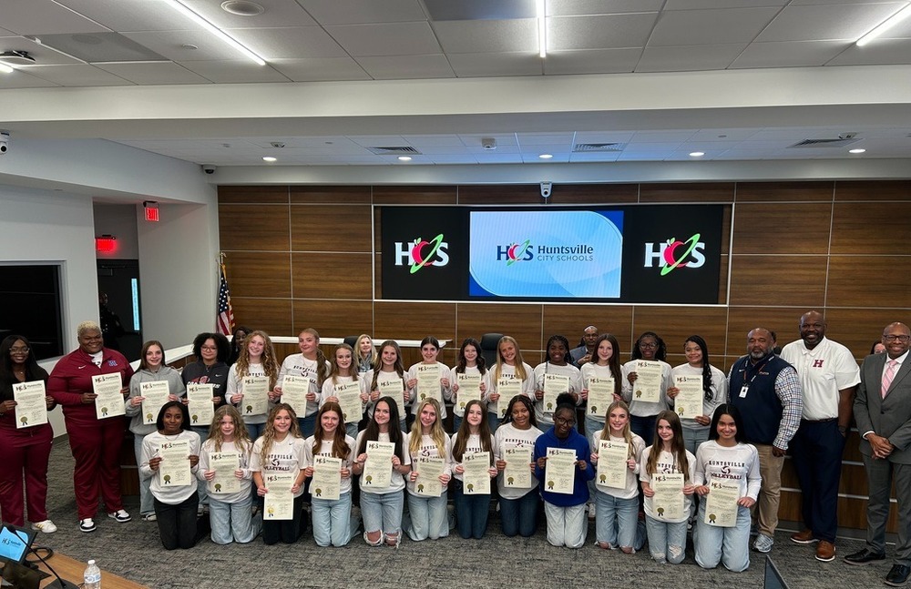 A group image of HJHS volleyball students with school district representatives. 