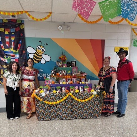 Faculty members standing in front of our schools ofrenda.