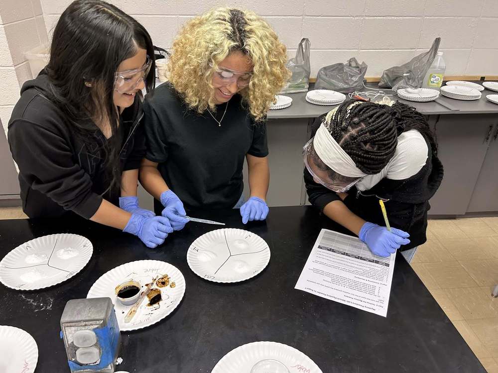 three students testing substances to identify which one is also sugar in the lab