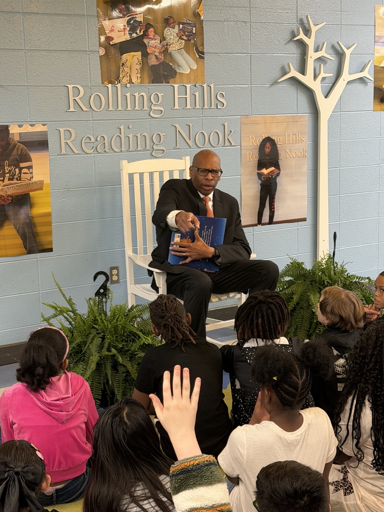 Superintendent Clarence Sutton reads to 3rd grade students in the Rolling Hills Reading Nook as they sit and listen.