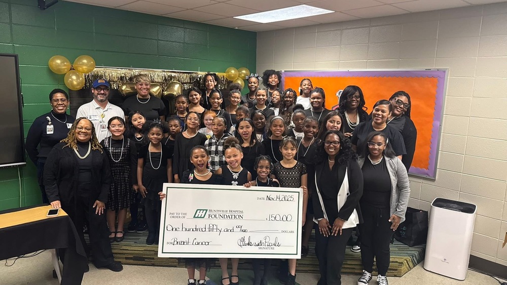 Girls with PEARLS and Mentors standing with Huntsville Foundation representatives . The girls are holding a $150 large check