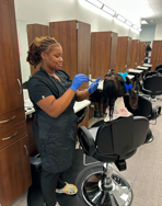 Returing Cosmetology student putting relaxer on a mannequin