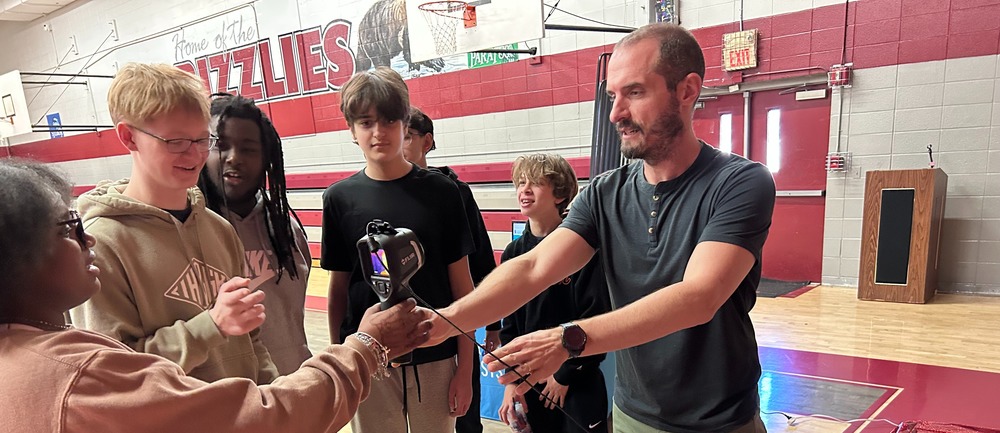 students looking at an infrared camera from an engineer at career day