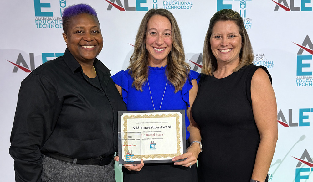 Bonnie Garrett and Heather Hall stand with Rachel Evans, who is holdering her K-12 Innovation Award certificate