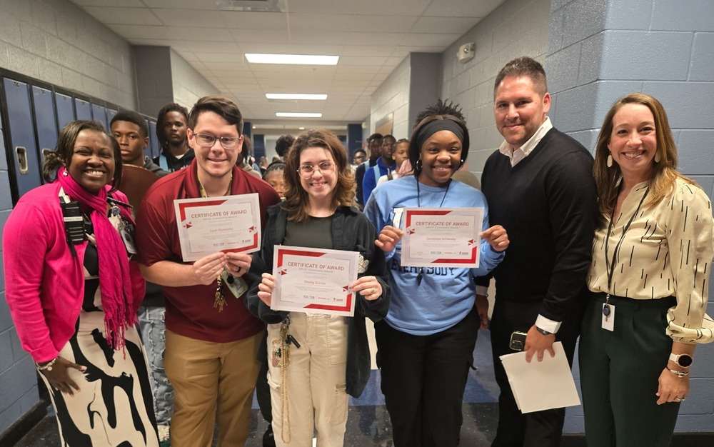 From left to right, Lee High School’s Mrs. Torain, Mr. Rominske, Mrs. Echols, and Mrs. McNealy stand with two representatives from Mazda Toyota while holding their Toyota DRIVE Grant certificates. The photo, taken in a school hallway with students in the background, captures the moment these educators were recognized for projects that will expand hands-on science learning for more than 1,000 students.