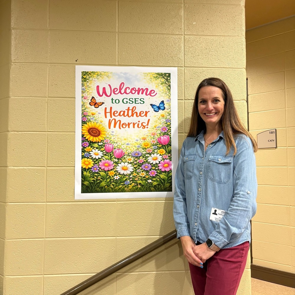Author Heather Morris stands in front of a poster that states "Welcome to GSES Heather Morris!"