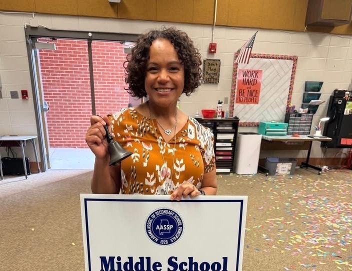 Mrs. Bardwell holding a sign that says Middle School Principal of the Year