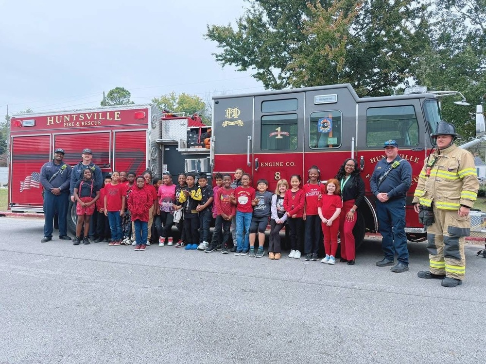 Ms. ford 3rd grade class pictured with 3 Huntsville Fire Rescue Station 8 Employees standing by red  fire truck