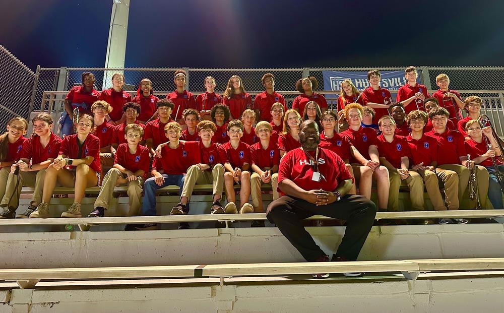 HJHS band members in red shirts sitting in stands