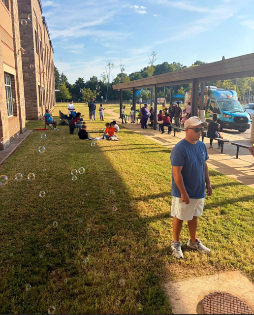 students, parents, and grandparents enjoying games on the school lawn