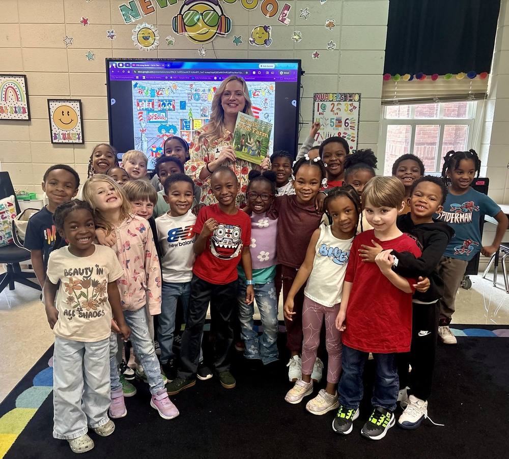 Students and readers standing up to take a picture that they listen to. during Read Across America week.