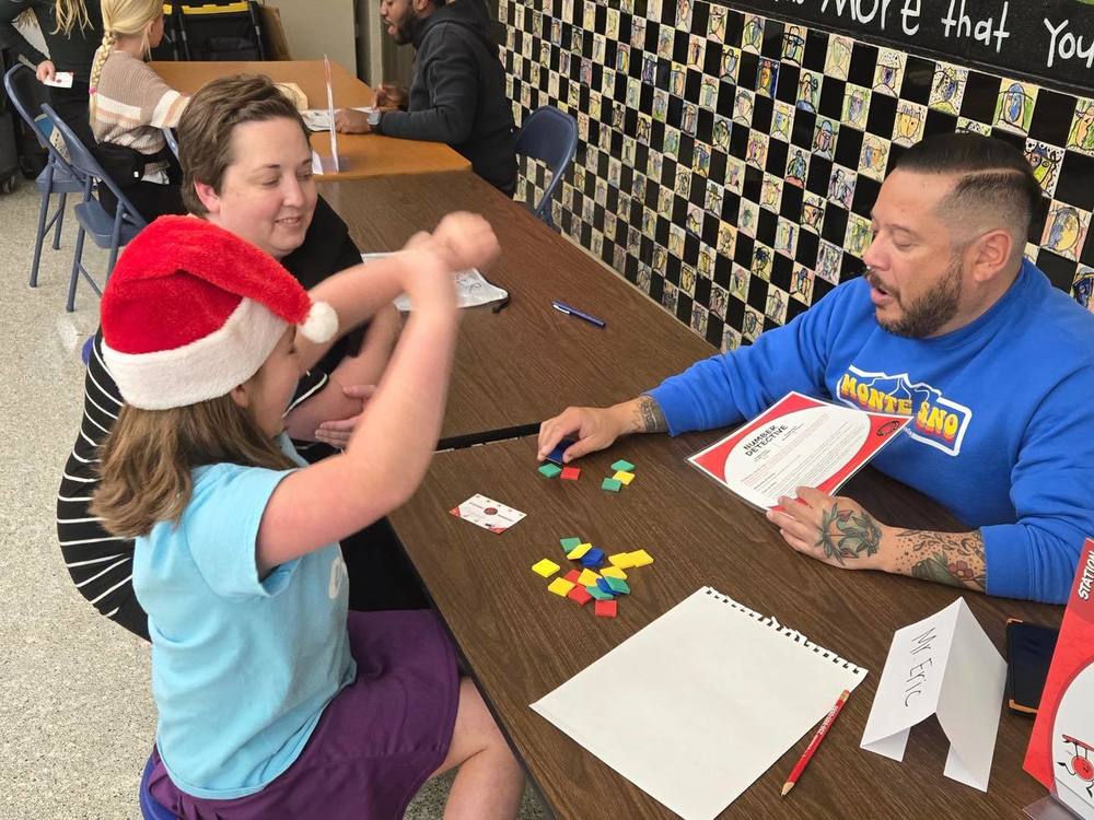 People sitting at table playing math game with color tiles and game mat