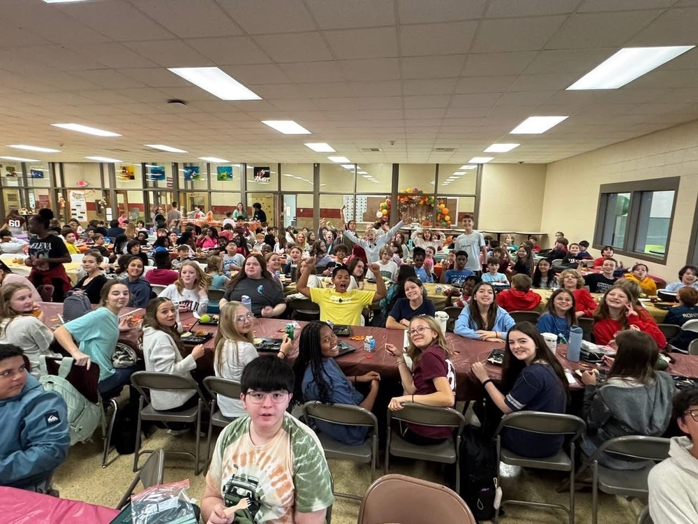A picture of a lot of students gathered together eating our school wide thanksgiving meal together