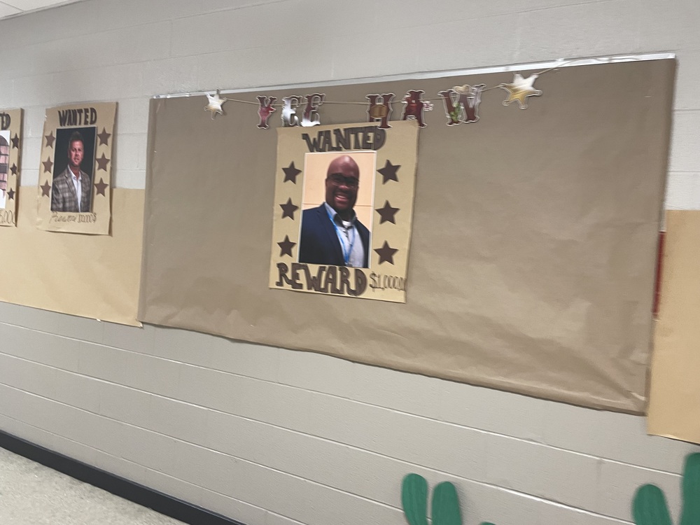 Picture of Bulletin Board on hall wall with a Wanted Reward Picture of Principal Richey