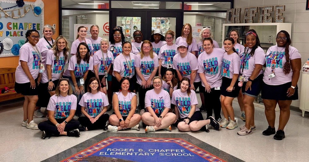 Chaffee Staff at the front of the school. Staff is wearing purple field day shirts