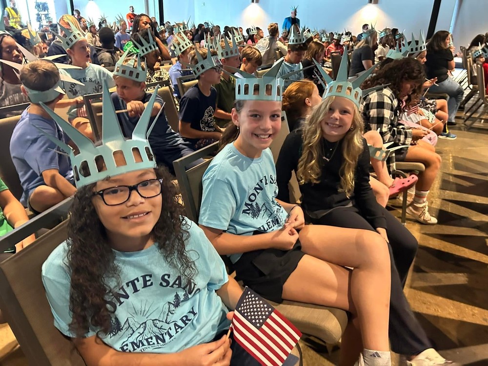 students sitting wearing blue shirts that say monte sano and wearing lady liberty hats