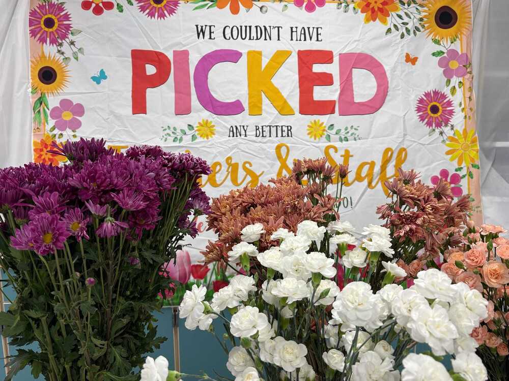 Colorful flower bouquets displayed in front of a Teacher Appreciation Week sign.